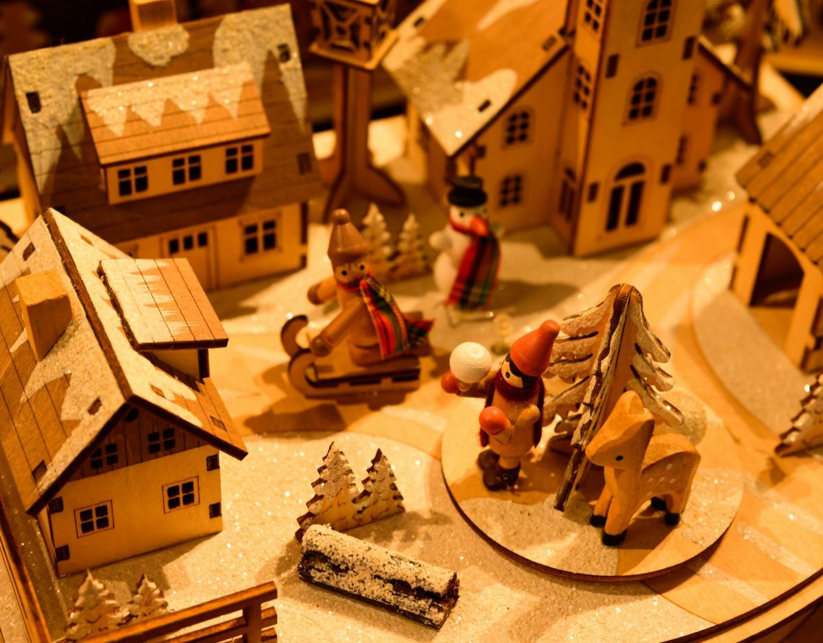 Holzdorf mit kleinen Häusern, Schlitten und Figuren im warmen Kerzenlicht