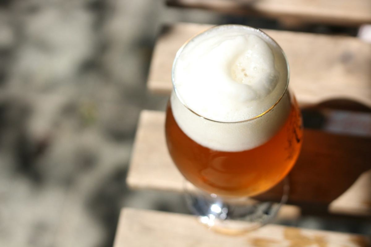 Glas Bier mit dicker Schaumkrone auf einem Holztisch