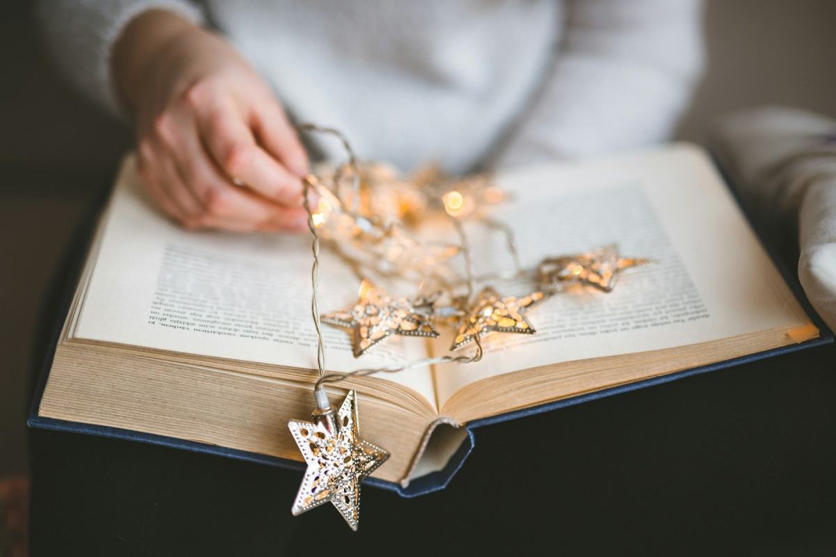 Aufgeschlagenes Buch, auf den Seiten liegt eine Lichterkette mit Sternen