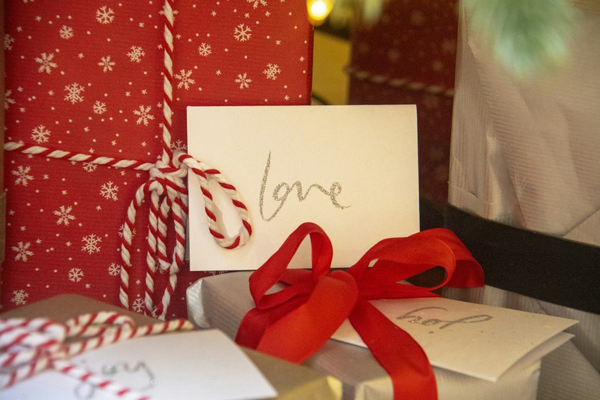 Geschenk mit roter Schleife und handgeschriebener Karte auf rotem Geschenkpapier