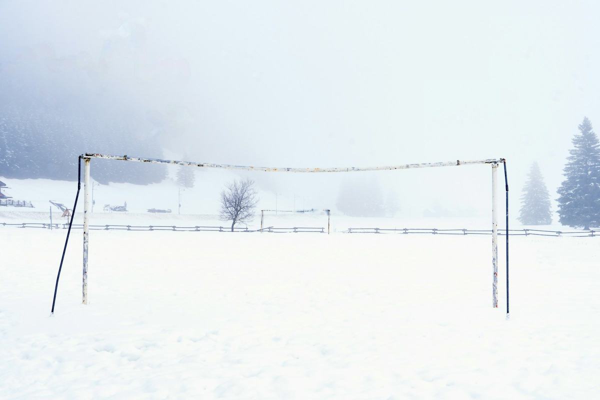 Verschneiter Bolzplatz mit Fußballtor im Nebel