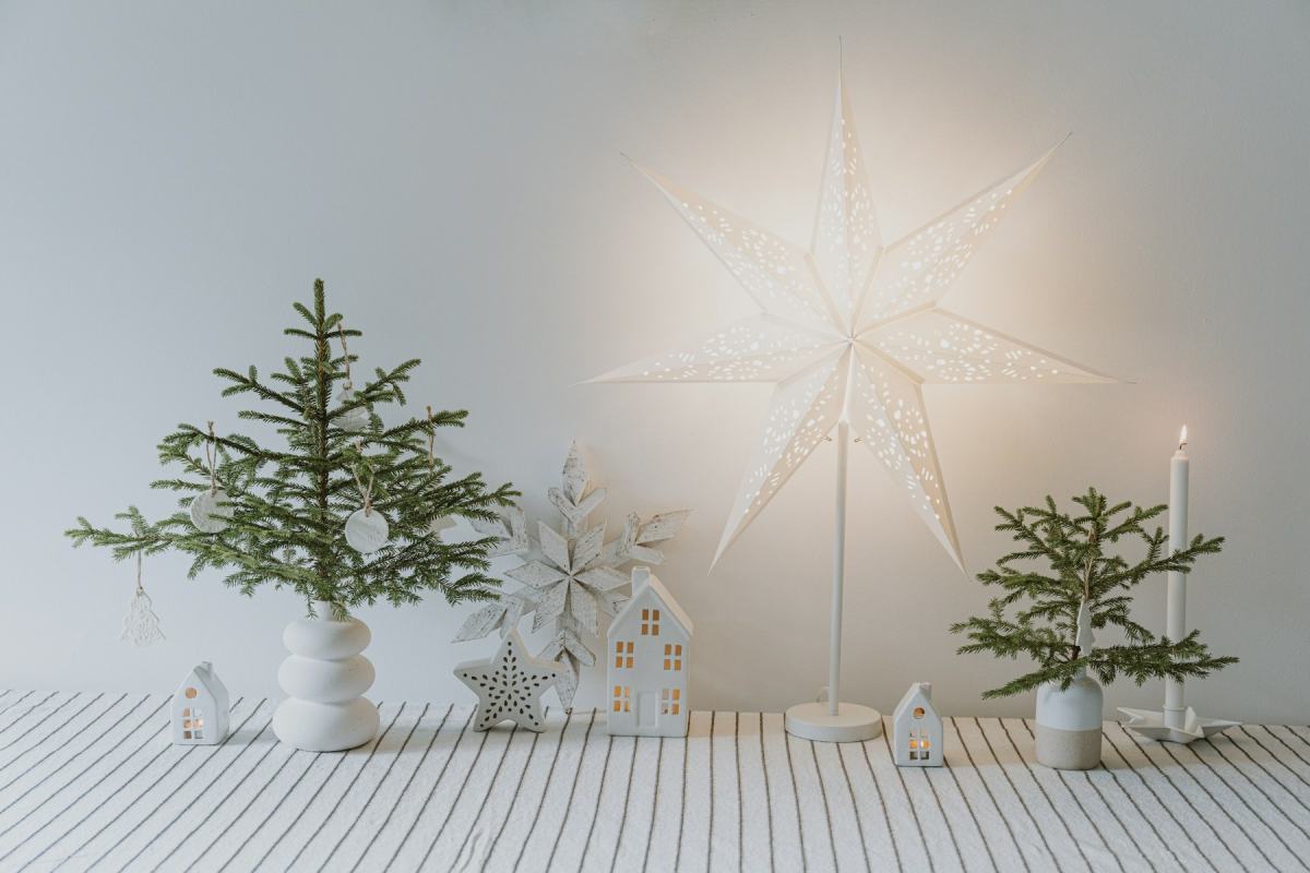 Schlichte skandinavische Weihnachtsdeko mit kleinen Tannen, Papierstern und weißen Häuschen