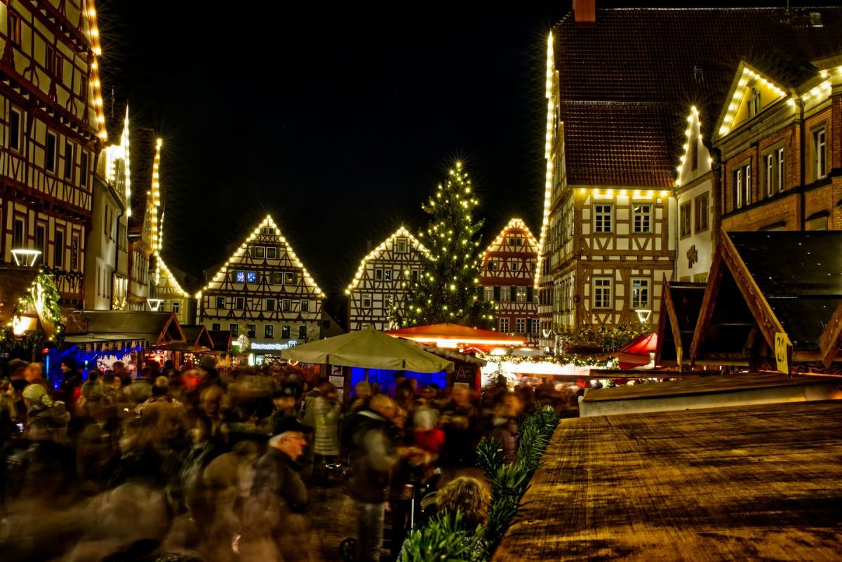 Weihnachtsmarkt am Abend zwischen beleuchteten Fachwerkhäusern mit großem Weihnachtsbaum