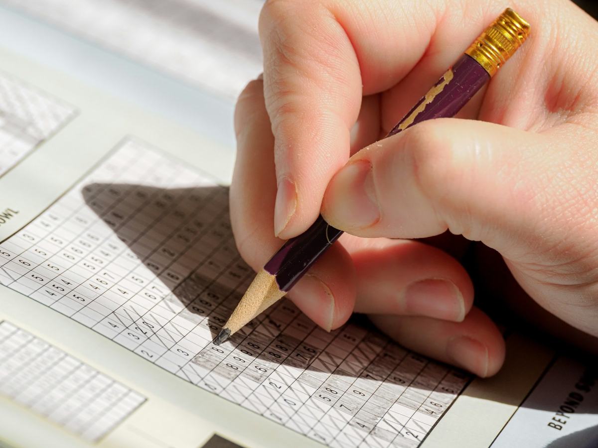 Hand füllt mit einem Bleistift ein Kreuzworträtsel aus