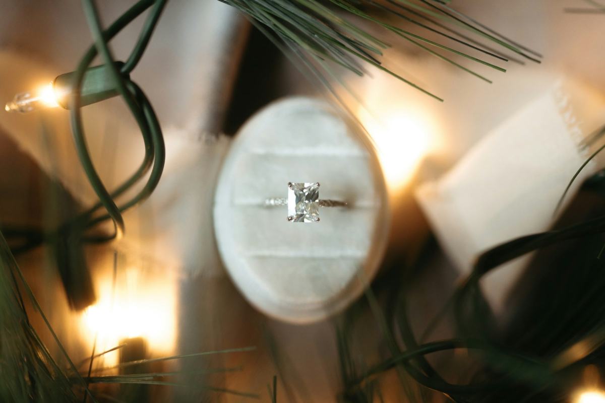 Ring in einer Schmuckschachtel zwischen Tannenzweigen und Lichterkette