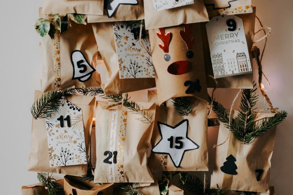 Adventskalender aus aufgehängten Papiertüten mit Zahlenanhängern und Tannenzweigen
