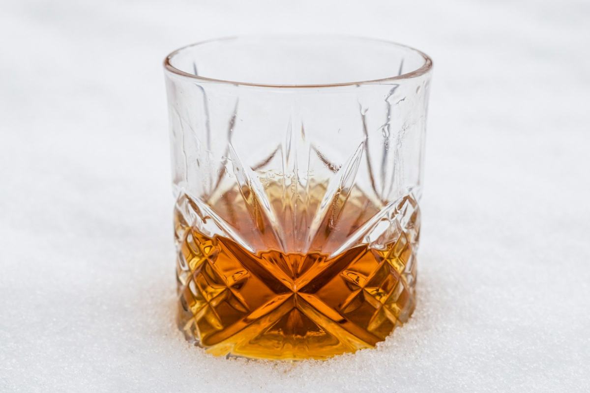 Kristallglas mit Whisky steht im Schnee