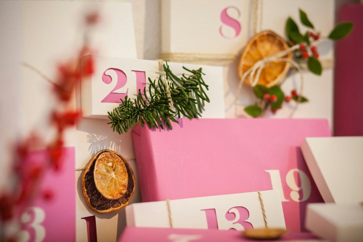 Leere Adventskalender-Schachteln in Rosa und Creme mit Zahlen, Tannengrün und Orangenscheiben